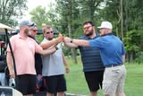 Golfers sharing a fist bump at the Merle Trumbull Golf Outing